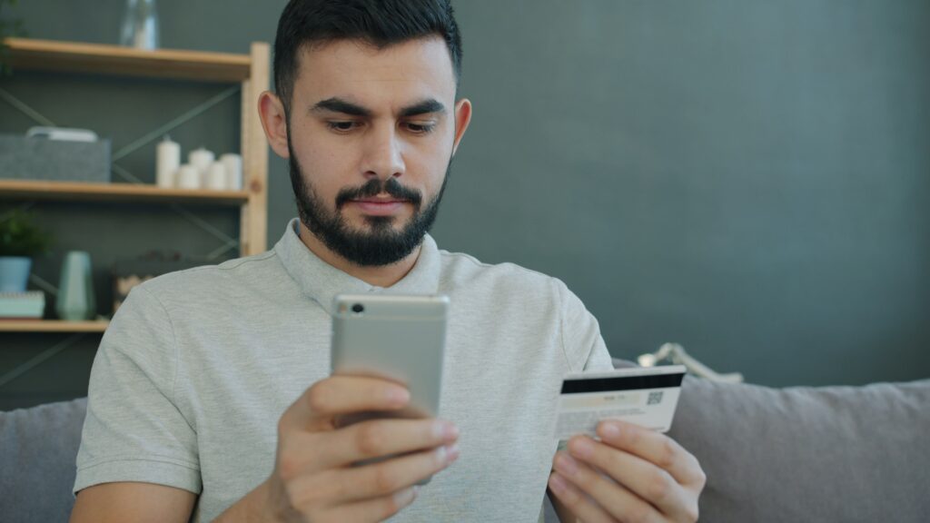 Hombre revisa su cuenta bancaria digital desde el celular, verificando la seguridad de su banco antes de confirmar una operación