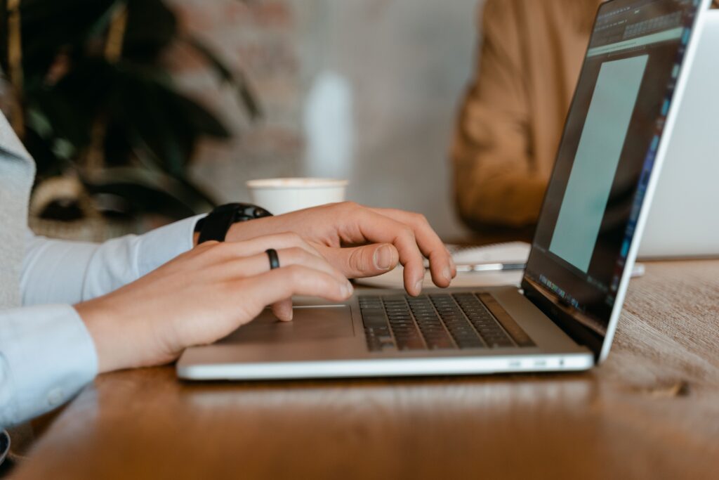 Manos escriben en una laptop, usando una herramienta de inteligencia artificial gratuita para resolver una tarea rápido